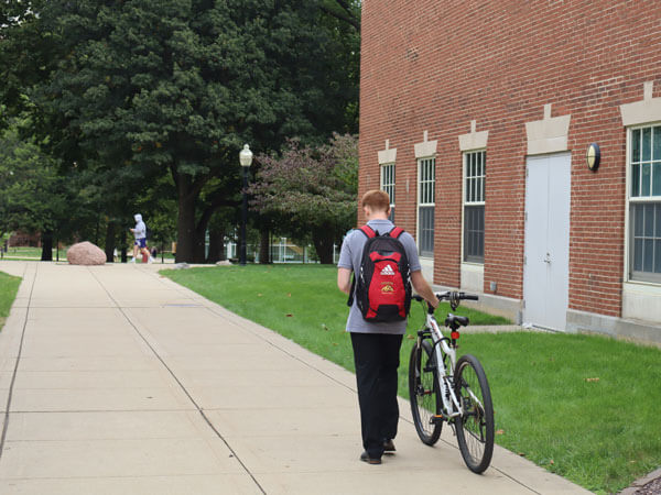 A student walks their bike in a dismount zone.