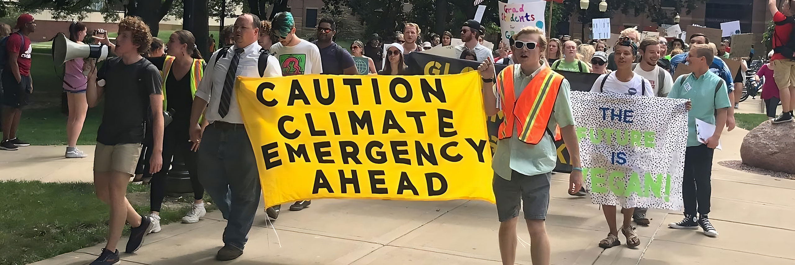 Student activists holding a sign saying 'Caution Climate Emergency'.