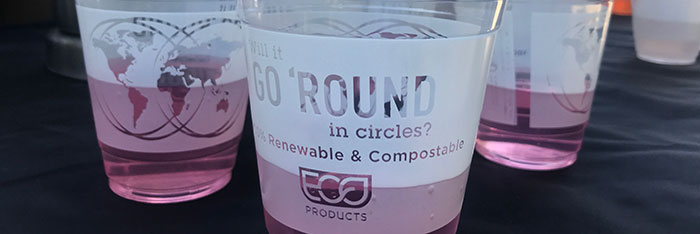 A table with several cups. The message on the cups reads, 'Will it go round in circles? 100% renewable and compostable. ECO products'.