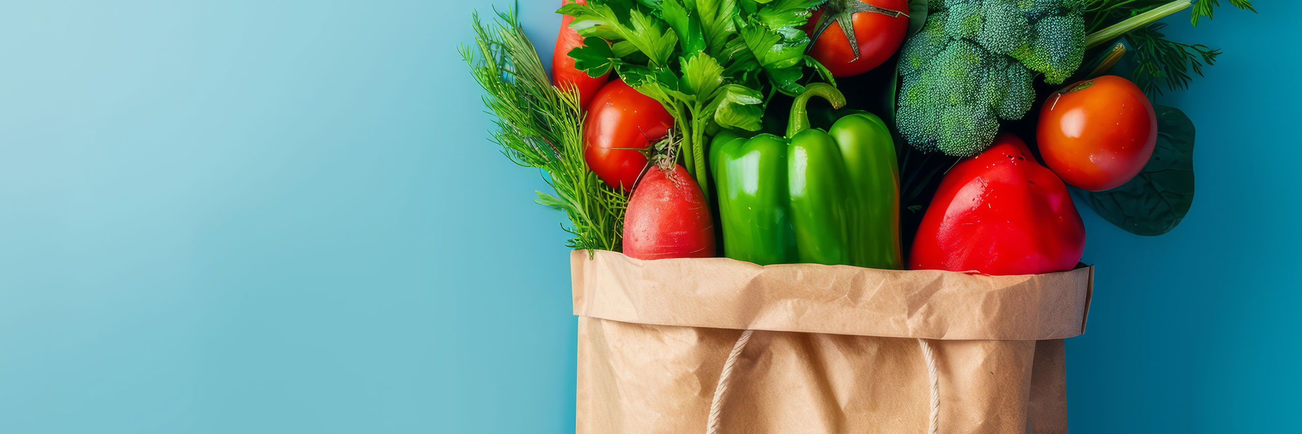 Paper grocery bag filled with fruits and vegetables in front of a blue background