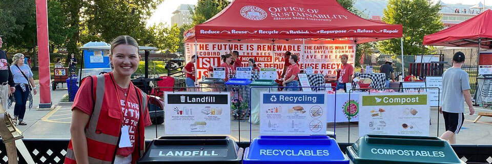 Student poses next to compost, recycling, and landfill bins.