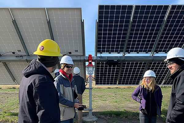 Instructor and students wear hard hats as they study on solar panels.