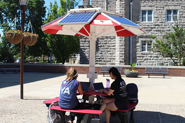 Students sit at a solar picnic table.