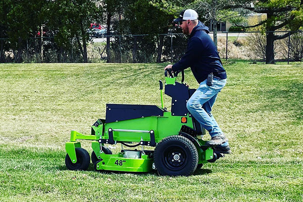 A grounds crew member mows the grass.