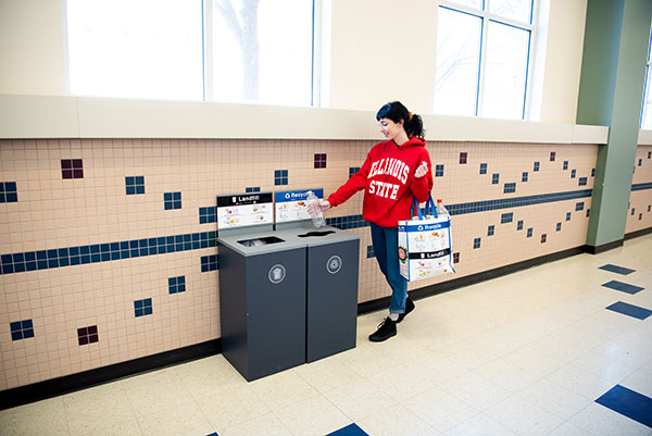 A student disposes of a cup in a centralized waste station.